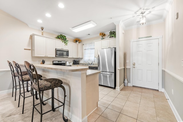 kitchen featuring kitchen peninsula, stainless steel appliances, ornamental molding, a kitchen bar, and white cabinets