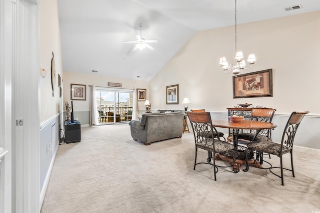 carpeted dining room featuring high vaulted ceiling and ceiling fan with notable chandelier