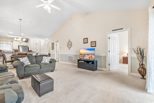 carpeted living room with high vaulted ceiling and ceiling fan with notable chandelier