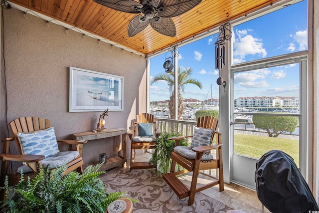 sunroom with wood ceiling, a water view, and ceiling fan