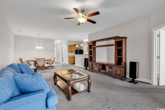 living room featuring ceiling fan with notable chandelier and light colored carpet