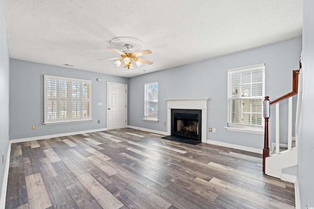 unfurnished living room with hardwood / wood-style floors, a textured ceiling, a healthy amount of sunlight, and ceiling fan