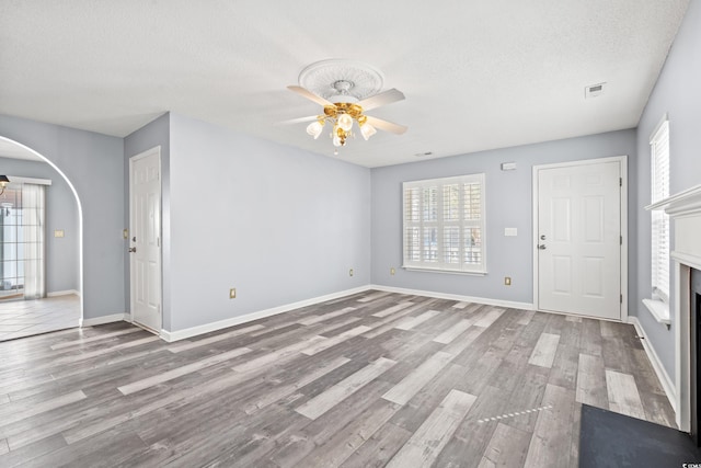 unfurnished living room featuring a textured ceiling, a healthy amount of sunlight, light wood-type flooring, and ceiling fan