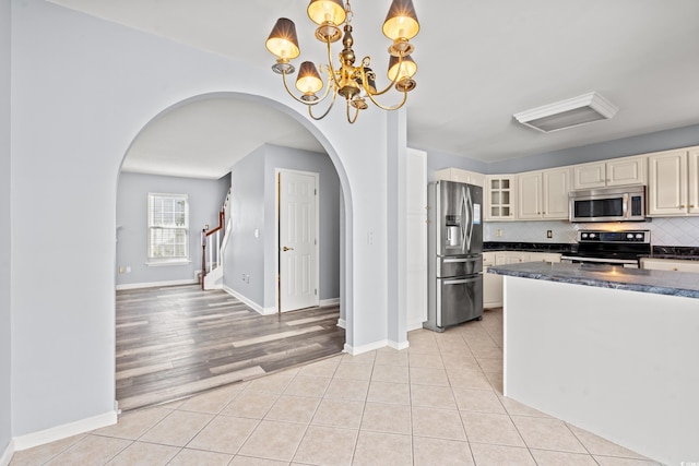 kitchen featuring decorative backsplash, cream cabinets, pendant lighting, light hardwood / wood-style floors, and stainless steel appliances