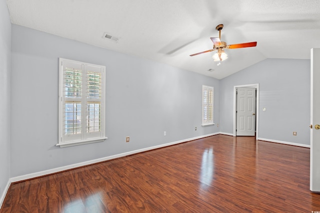 empty room featuring dark wood-type flooring, vaulted ceiling, a textured ceiling, and ceiling fan