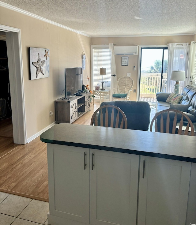 kitchen featuring ornamental molding, a wealth of natural light, a wall mounted air conditioner, and a textured ceiling