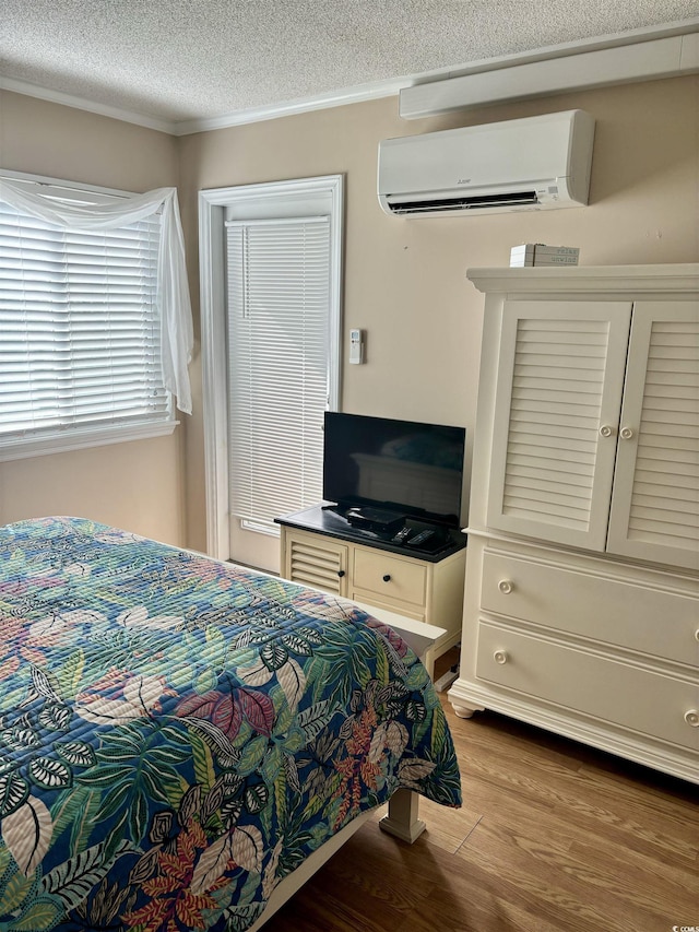 bedroom featuring a wall unit AC, a textured ceiling, and wood finished floors