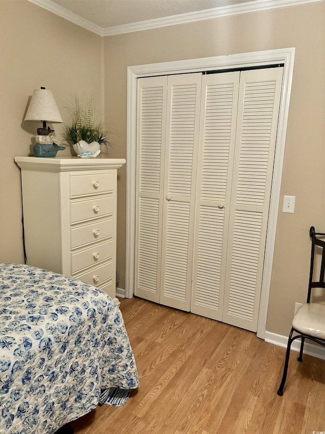 bedroom with ornamental molding, a closet, light wood-style flooring, and baseboards