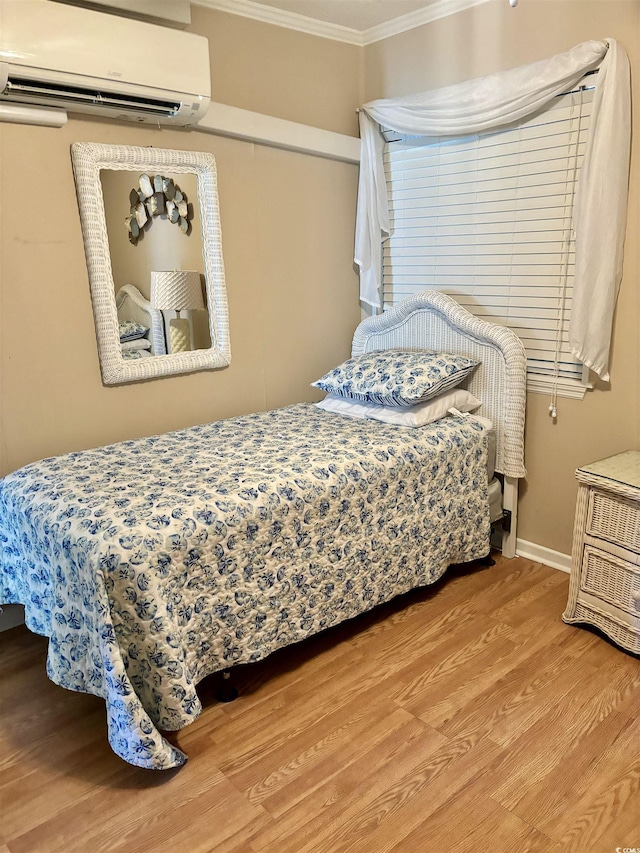 bedroom featuring baseboards, an AC wall unit, wood finished floors, and crown molding