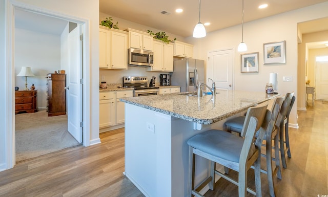 kitchen with sink, hanging light fixtures, stainless steel appliances, white cabinets, and light stone counters