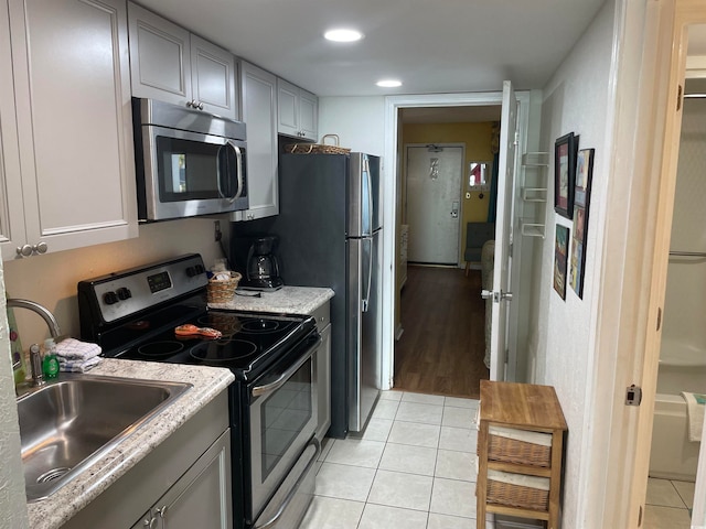 kitchen with appliances with stainless steel finishes, gray cabinetry, and light tile patterned floors