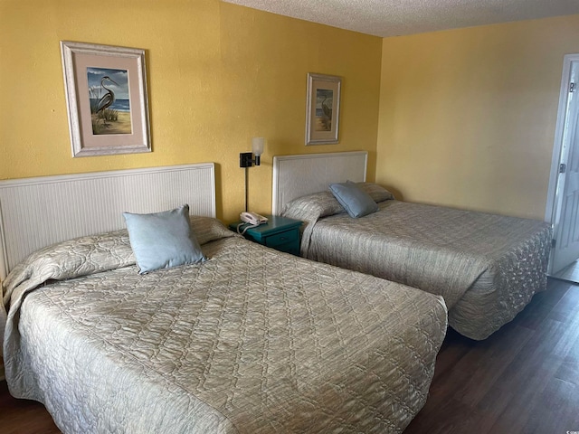 bedroom with a textured ceiling and dark wood-type flooring