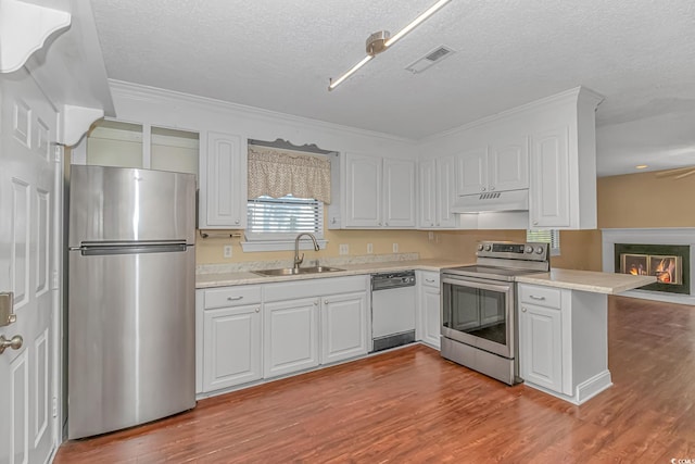 kitchen featuring kitchen peninsula, white cabinets, appliances with stainless steel finishes, light hardwood / wood-style floors, and sink