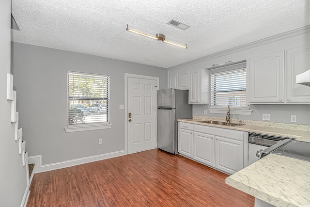 kitchen featuring visible vents, light countertops, freestanding refrigerator, wood finished floors, and a sink