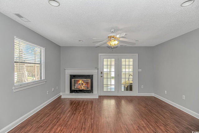unfurnished living room with visible vents, baseboards, wood finished floors, a glass covered fireplace, and a ceiling fan