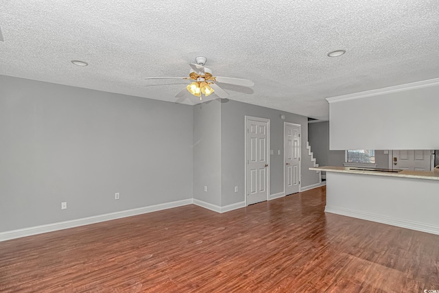 unfurnished living room featuring baseboards, ceiling fan, stairs, wood finished floors, and a textured ceiling