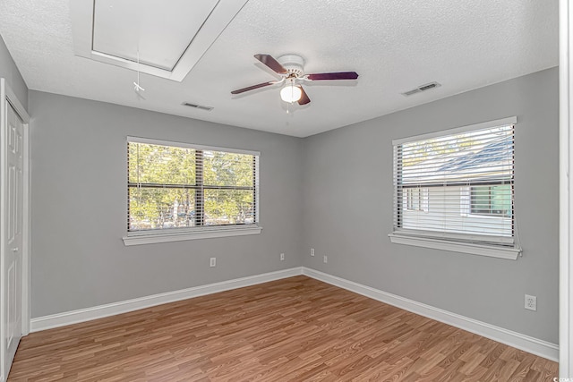 unfurnished room with visible vents, a healthy amount of sunlight, attic access, and ceiling fan