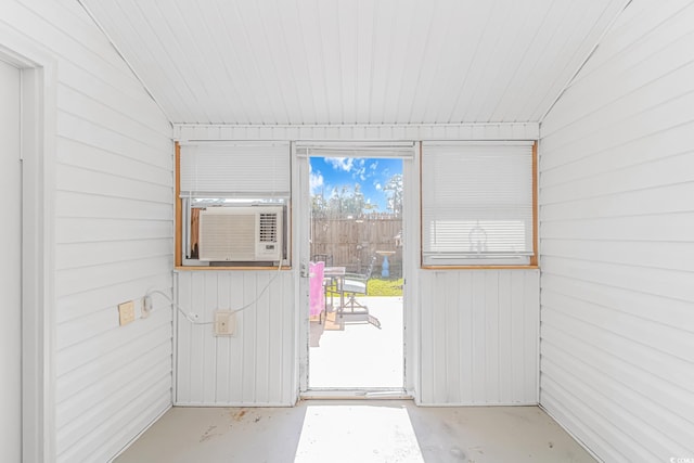 doorway to outside featuring wood walls, cooling unit, and concrete flooring