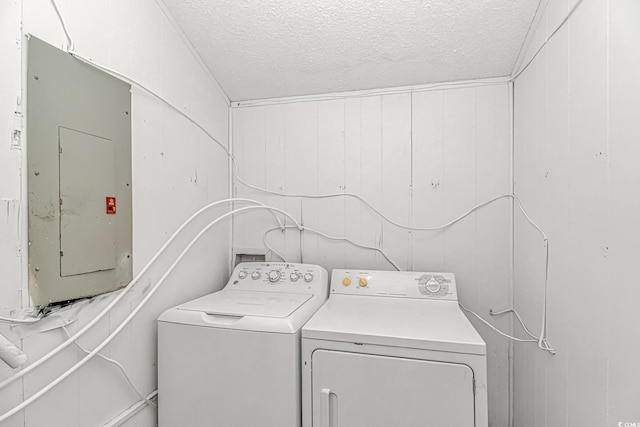 washroom featuring washing machine and clothes dryer, laundry area, electric panel, and a textured ceiling