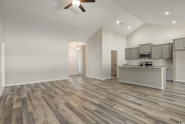 unfurnished living room with high vaulted ceiling, ceiling fan, and light hardwood / wood-style floors