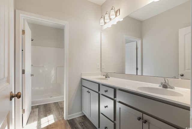 bathroom with walk in shower, vanity, and wood-type flooring