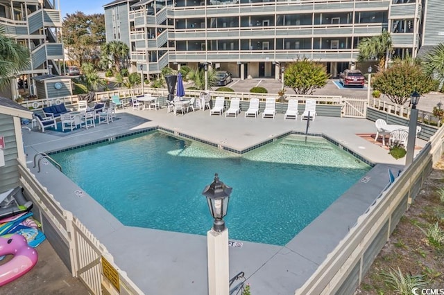 pool with a patio area and fence