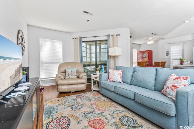 living room featuring a ceiling fan, visible vents, and wood finished floors