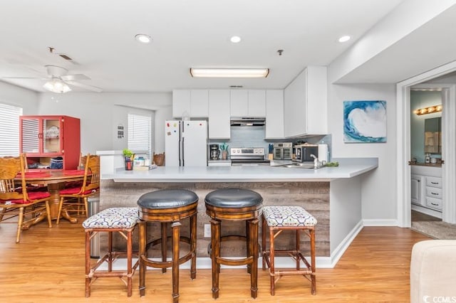 kitchen featuring light wood-type flooring, kitchen peninsula, ceiling fan, stainless steel appliances, and white cabinets