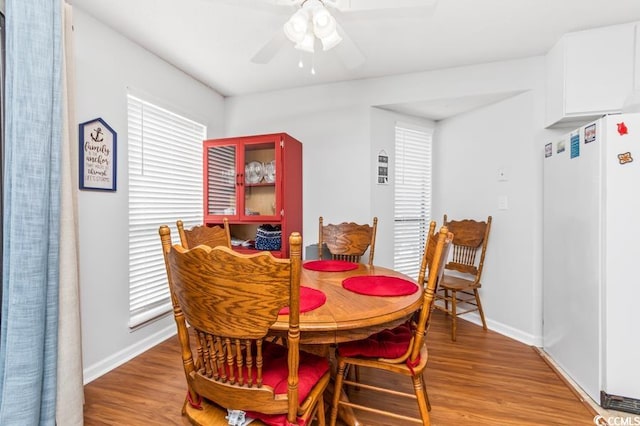 dining room featuring light wood-style floors, baseboards, and a ceiling fan
