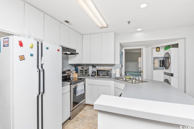 kitchen featuring visible vents, stacked washer and dryer, under cabinet range hood, a sink, and stainless steel appliances