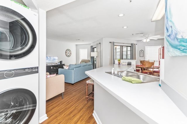 kitchen featuring stacked washer and clothes dryer, sink, a kitchen bar, light hardwood / wood-style floors, and ceiling fan