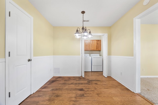 unfurnished dining area featuring dark wood-type flooring, a notable chandelier, and washing machine and dryer