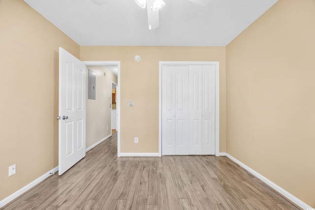 unfurnished bedroom with a closet, ceiling fan, electric panel, and light hardwood / wood-style flooring