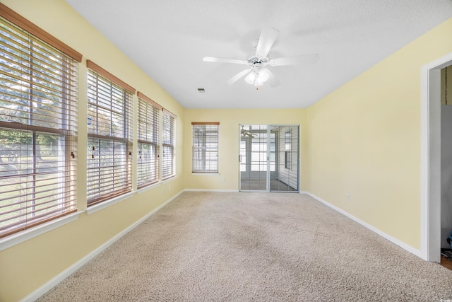 carpeted empty room with ceiling fan and a wealth of natural light