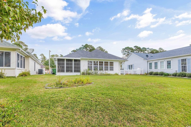 back of property featuring a yard, a sunroom, and central AC