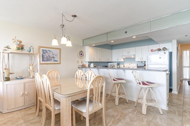 dining space featuring a textured ceiling, an inviting chandelier, and light tile patterned floors