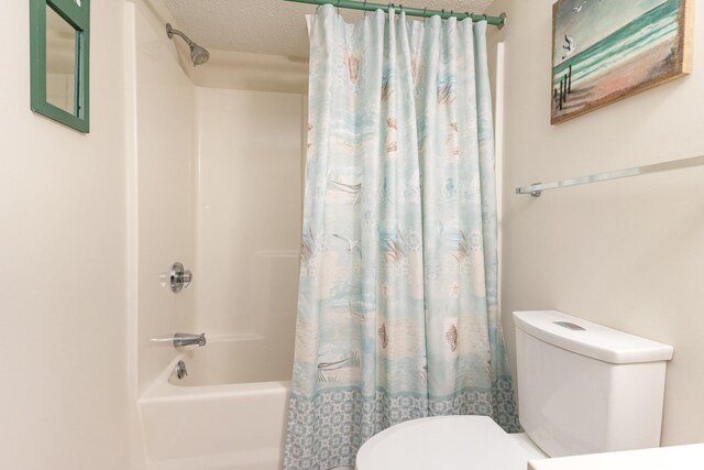 bathroom with toilet, a textured ceiling, and shower / bath combo with shower curtain