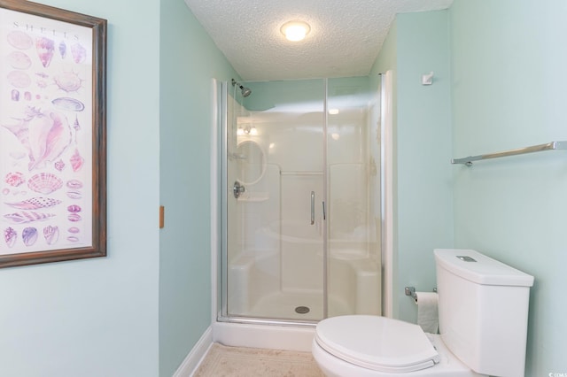 bathroom with toilet, a textured ceiling, tile patterned flooring, and a shower with door