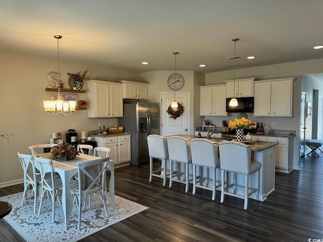 kitchen featuring an island with sink, dark hardwood / wood-style flooring, decorative light fixtures, white cabinets, and stainless steel fridge with ice dispenser