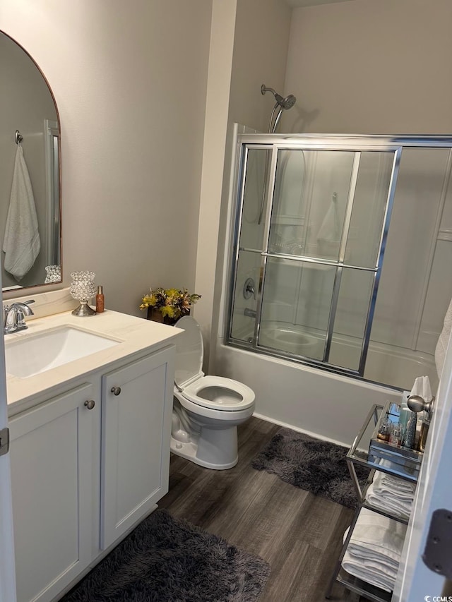 full bathroom with toilet, enclosed tub / shower combo, hardwood / wood-style flooring, and vanity