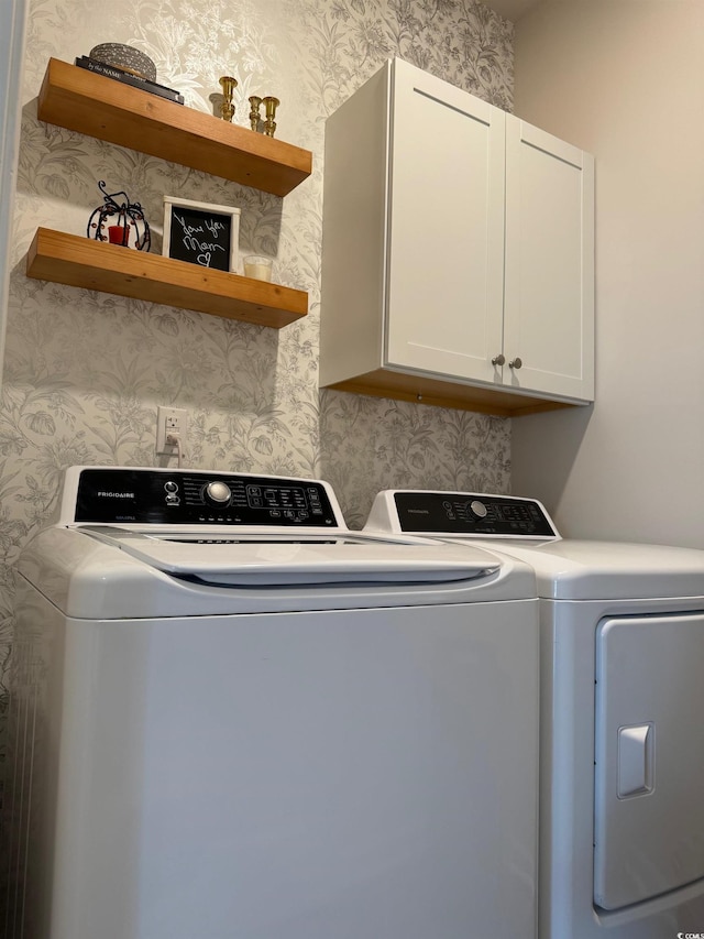 clothes washing area with cabinets and washer and clothes dryer