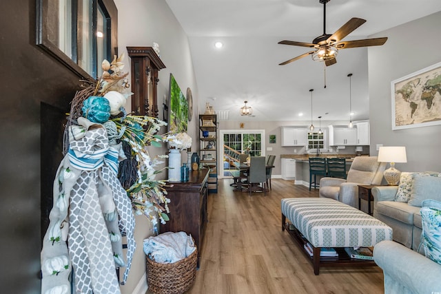 living room featuring ceiling fan, lofted ceiling, and light hardwood / wood-style flooring