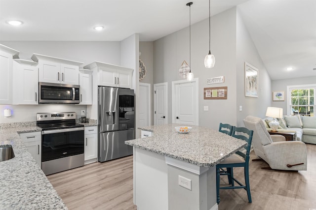 kitchen with light wood-type flooring, a breakfast bar, stainless steel appliances, white cabinets, and a center island