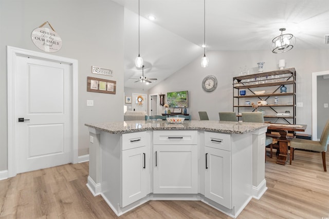 kitchen with white cabinetry, hanging light fixtures, vaulted ceiling, and light wood-type flooring