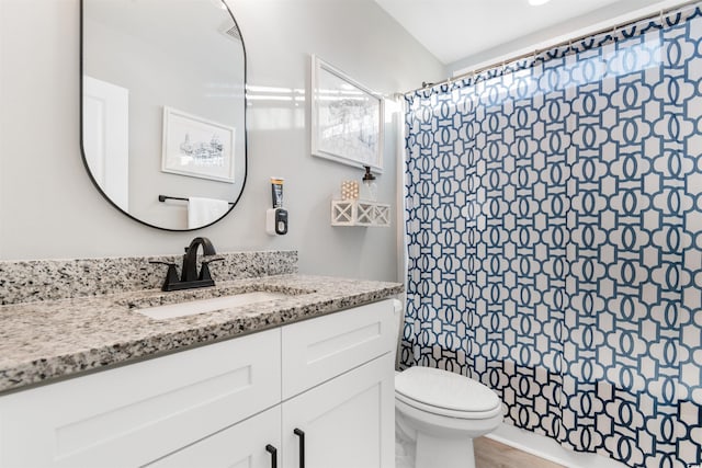 bathroom with hardwood / wood-style floors, vanity, toilet, and walk in shower