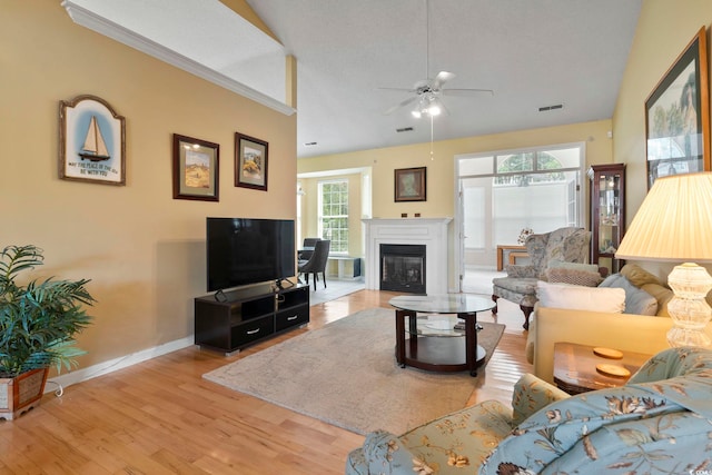 living room with crown molding, light wood-type flooring, a healthy amount of sunlight, and ceiling fan