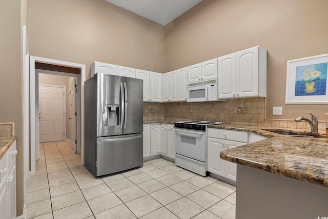 kitchen featuring white appliances, sink, stone counters, white cabinets, and high vaulted ceiling