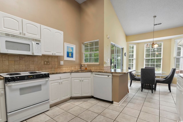 kitchen with white appliances, dark stone countertops, a textured ceiling, and white cabinets