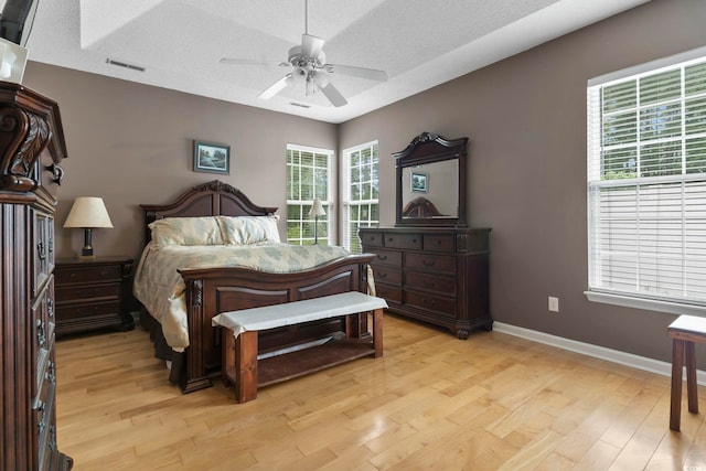 bedroom with ceiling fan, a textured ceiling, and light hardwood / wood-style flooring