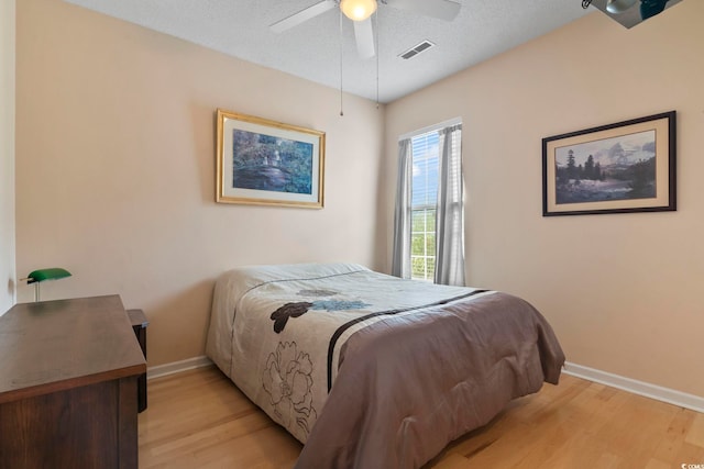 bedroom featuring a textured ceiling, light wood-type flooring, and ceiling fan